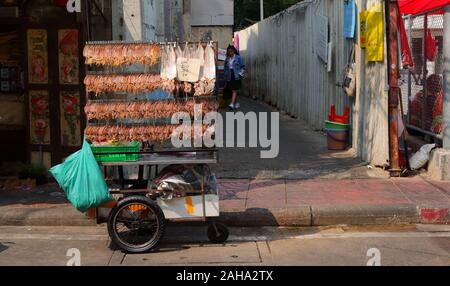 Bangkok, Thailand-December 26 2019 : Dried squids holding by clips and hanging on vendor cart, they will be grilled and rolled before selling Stock Photo
