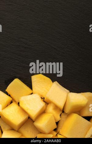 Close up of juicy pineapple cubes on dark shale plate Stock Photo