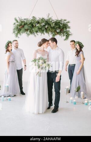 gorgeous bride with peony bouquet and stylish groom posing with bridesmaids and groomsmen on wedding day. luxury wedding couple having fun with friend Stock Photo