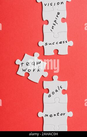 top view of white connected jigsaw near puzzle piece with words isolated on red Stock Photo