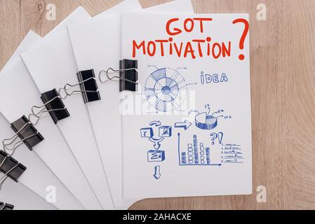 top view of white paper sheets arranged with binder clips, got motivation question and infographics illustration on wooden surface, business concept Stock Photo