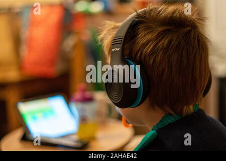 A three year old child watching a tablet or mobile device wearing headphones Stock Photo
