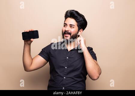 Young man hold telephone in arms make take selfie isolated on beige background Stock Photo