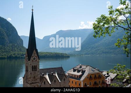 18.06.2019, Hallstatt, Upper Austria, Austria - View of the small village with church, the Hallstaetter lake and mountains in the background. The vill Stock Photo