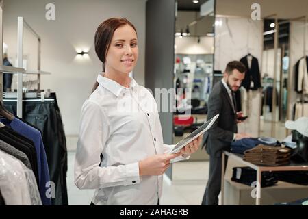 Pretty young successful consultant of boutique using digital tablet at work Stock Photo