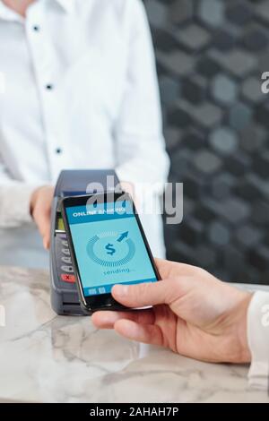 Hand of young contemporary man holding smartphone over payment machine Stock Photo