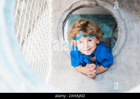 Cheerful cute little boy in costume of superman looking at you during play Stock Photo