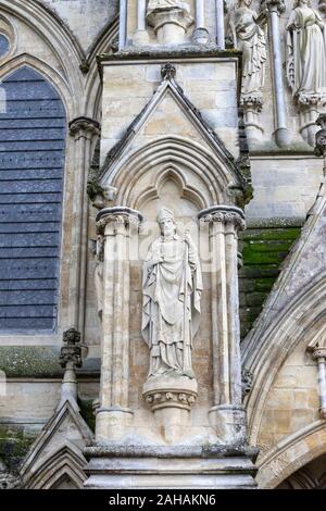 Stone statue of St Osmund holding two books in his right hand and a staff in his left hand. Salisbury Cathedral, Salisbury, Wiltshire, UK Stock Photo