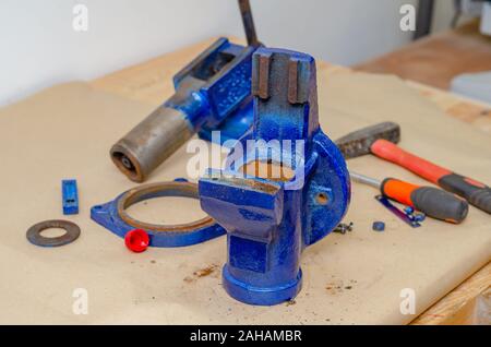 Parts of disassembled metal vise on the table in the workshop. Heavy Tool Repair Stock Photo