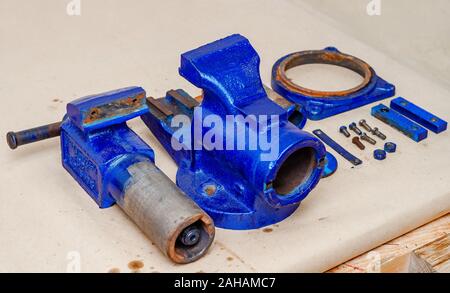 Parts of disassembled metal vise on the table in the workshop. Heavy Tool Repair Stock Photo