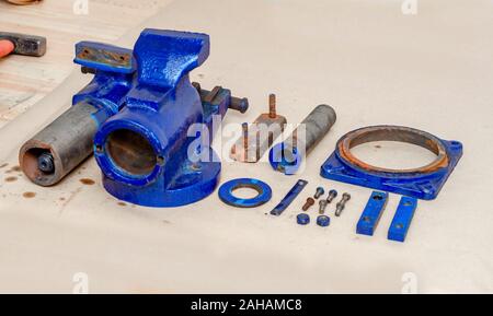 Parts of disassembled metal vise on the table in the workshop. Heavy Tool Repair Stock Photo