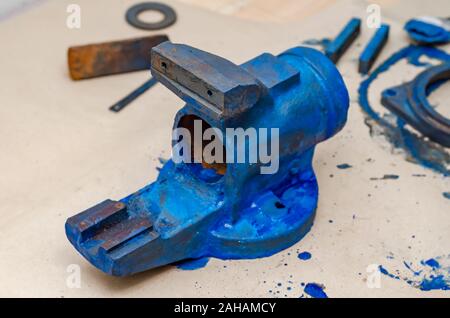 Parts of disassembled metal vise on the table in the workshop. Heavy Tool Repair Stock Photo