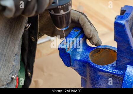 Worker man dismantles old metal vice in workshop. Stock Photo