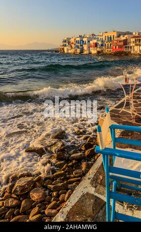 Sunset view of the famous pictorial Little Venice in Mykonos island. Splashing waves over bars and restaurants of Mykonos old town, Cyclades, Greece. Stock Photo