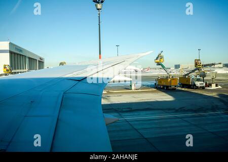 Boeing 737 wing  worker is de-icing a commercial airliner wing in Toronto. AIRCRAFT IS DE-ICED ON THE RUNWAY BEFORE TAKING OFF. Stock Photo