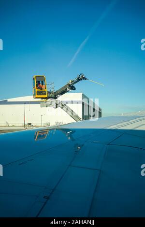 Boeing 737 wing  worker is de-icing a commercial airliner wing in Toronto. AIRCRAFT IS DE-ICED ON THE RUNWAY BEFORE TAKING OFF. Stock Photo