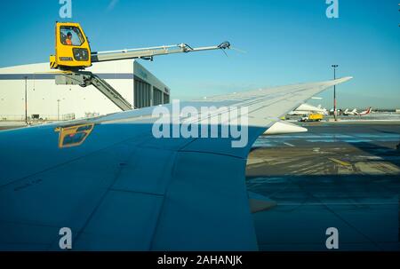 Boeing 737 wing  worker is de-icing a commercial airliner wing in Toronto. AIRCRAFT IS DE-ICED ON THE RUNWAY BEFORE TAKING OFF. Stock Photo