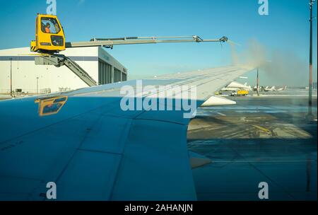 Boeing 737 wing  worker is de-icing a commercial airliner wing in Toronto. AIRCRAFT IS DE-ICED ON THE RUNWAY BEFORE TAKING OFF. Stock Photo