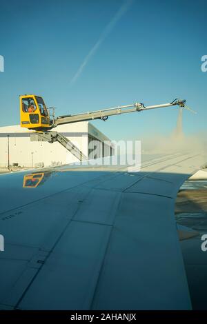 Boeing 737 wing  worker is de-icing a commercial airliner wing in Toronto. AIRCRAFT IS DE-ICED ON THE RUNWAY BEFORE TAKING OFF. Stock Photo