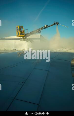 Boeing 737 wing  worker is de-icing a commercial airliner wing in Toronto. AIRCRAFT IS DE-ICED ON THE RUNWAY BEFORE TAKING OFF. Stock Photo