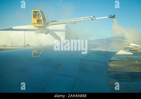 Boeing 737 wing  worker is de-icing a commercial airliner wing in Toronto. AIRCRAFT IS DE-ICED ON THE RUNWAY BEFORE TAKING OFF. Stock Photo