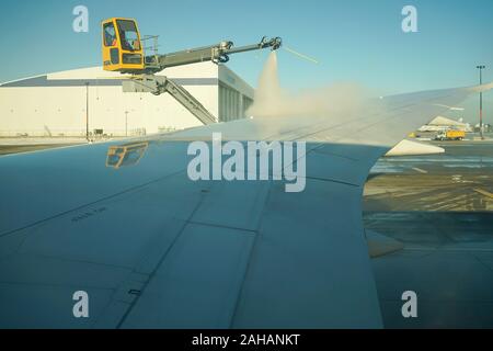 Boeing 737 wing  worker is de-icing a commercial airliner wing in Toronto. AIRCRAFT IS DE-ICED ON THE RUNWAY BEFORE TAKING OFF. Stock Photo