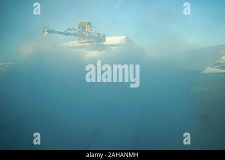 Boeing 737 wing  worker is de-icing a commercial airliner wing in Toronto. AIRCRAFT IS DE-ICED ON THE RUNWAY BEFORE TAKING OFF. Stock Photo