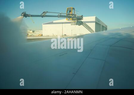 Boeing 737 wing  worker is de-icing a commercial airliner wing in Toronto. AIRCRAFT IS DE-ICED ON THE RUNWAY BEFORE TAKING OFF. Stock Photo