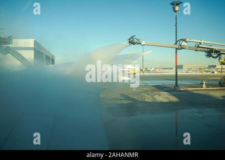 Boeing 737 wing  worker is de-icing a commercial airliner wing in Toronto. AIRCRAFT IS DE-ICED ON THE RUNWAY BEFORE TAKING OFF. Stock Photo