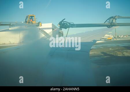 Boeing 737 wing  worker is de-icing a commercial airliner wing in Toronto. AIRCRAFT IS DE-ICED ON THE RUNWAY BEFORE TAKING OFF. Stock Photo