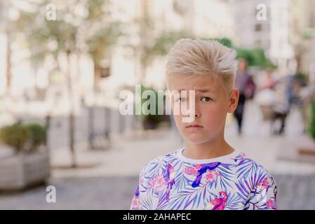 portrait of cute handsome blonde eleven old boy (teenager) lost in the city. Growing up, chilhood, separating concept Stock Photo