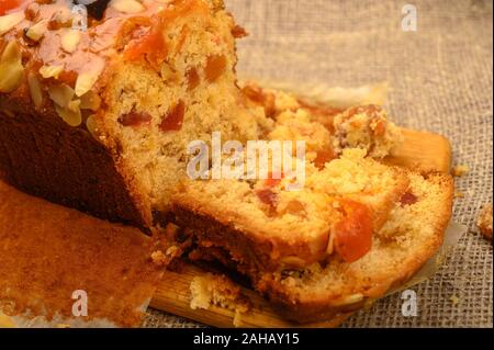 A sliced home-made Christmas cake on a wooden Board on a table covered with a homespun cloth Stock Photo