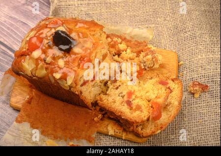 A sliced home-made Christmas cake on a wooden Board on a table covered with a homespun cloth Stock Photo