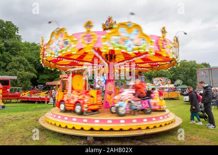 Moving children's roundabout at a summer country fair after the Thelwall Rose Queen procession 2019 Stock Photo