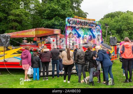 People watching the Cliffhanger fairground ride in wet weather in summer after the Thelwall Rose Queen procession 2019 Stock Photo