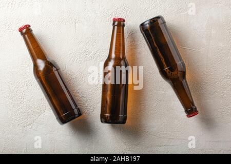 Three bottles of beer on the background of light concrete. Stock Photo