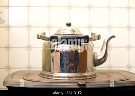 Old Kettle on the antique burning stove, vintage design used for a long time Stock Photo