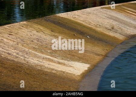 Completely dried man made waterfall during summer low water levels and drought season revealing concrete foundation covered with moss Stock Photo