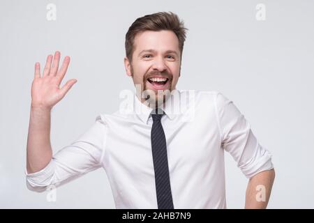 Handsome caucasian man in tie and whie shirt with glasses saluting waving hand. Stock Photo