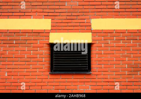 Retro vintage old red brick wall with yellow parts and single closed window with metal blinds protection texture background wallpaper Stock Photo
