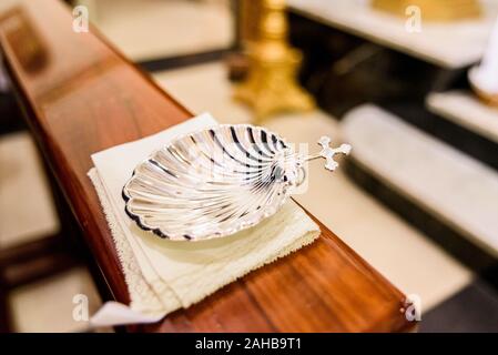 Silver shell for holy water in Christian religious baptism. Stock Photo