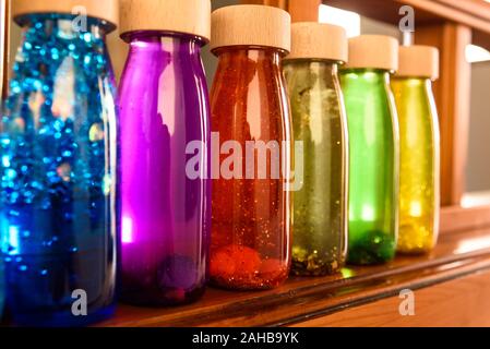 Collection of bottles of calm, plastic with wooden stopper, toy filled with liquids and materials of bright colors and glitter to relax children when Stock Photo