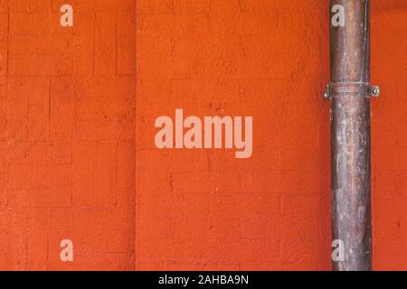 Copper pipe on bright orange concrete brick wall vintage background texture Stock Photo
