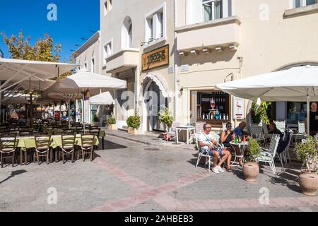 Kos, Greece - September 21st 2019: - People drinking in an outdoor cafe in Elefterias Square. This is the centre of Kos town Stock Photo
