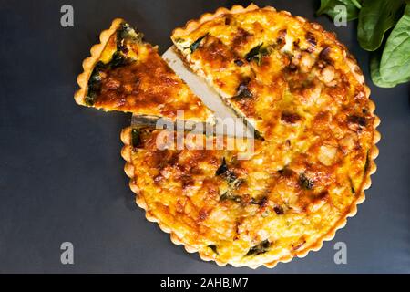 top view freshly bake leek bacon spinach quiche on dark background Stock Photo