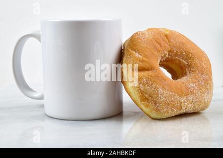 A delicious breakfast featuring a fresh sugar donut and a cup of coffee on a marble tabletop. Stock Photo