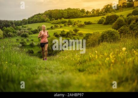 A middle-aged woman runs through the hills Stock Photo