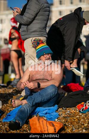 December 25, 2019: Brighton, UK. 25 December 2019. Hundreds of people gather on Brighton beach for their annual Christmas Day swim. Despite the council raising safety concerns and the big sea waves, several swimmers have taken part in this year's Christmas dip off the Brighton beach in their bikinis, swimming shorts, and Santa Claus outfits Credit: Matt Duckett/IMAGESLIVE/ZUMA Wire/Alamy Live News Stock Photo