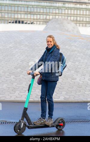 Woman driving electric scooter on the road in Finland Stock Photo