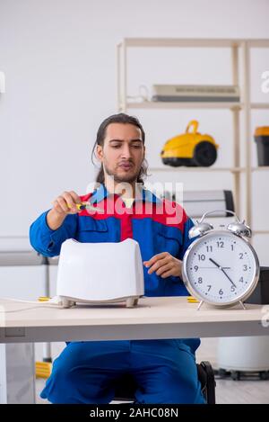 The young male contractor repairing toaster at workshop Stock Photo